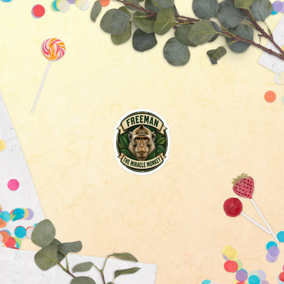 Klistermærke med Freeman The Miracle Monkey badge med en abe i grønt, 7,5 x 7,5 cm, på en lys baggrund med blomster