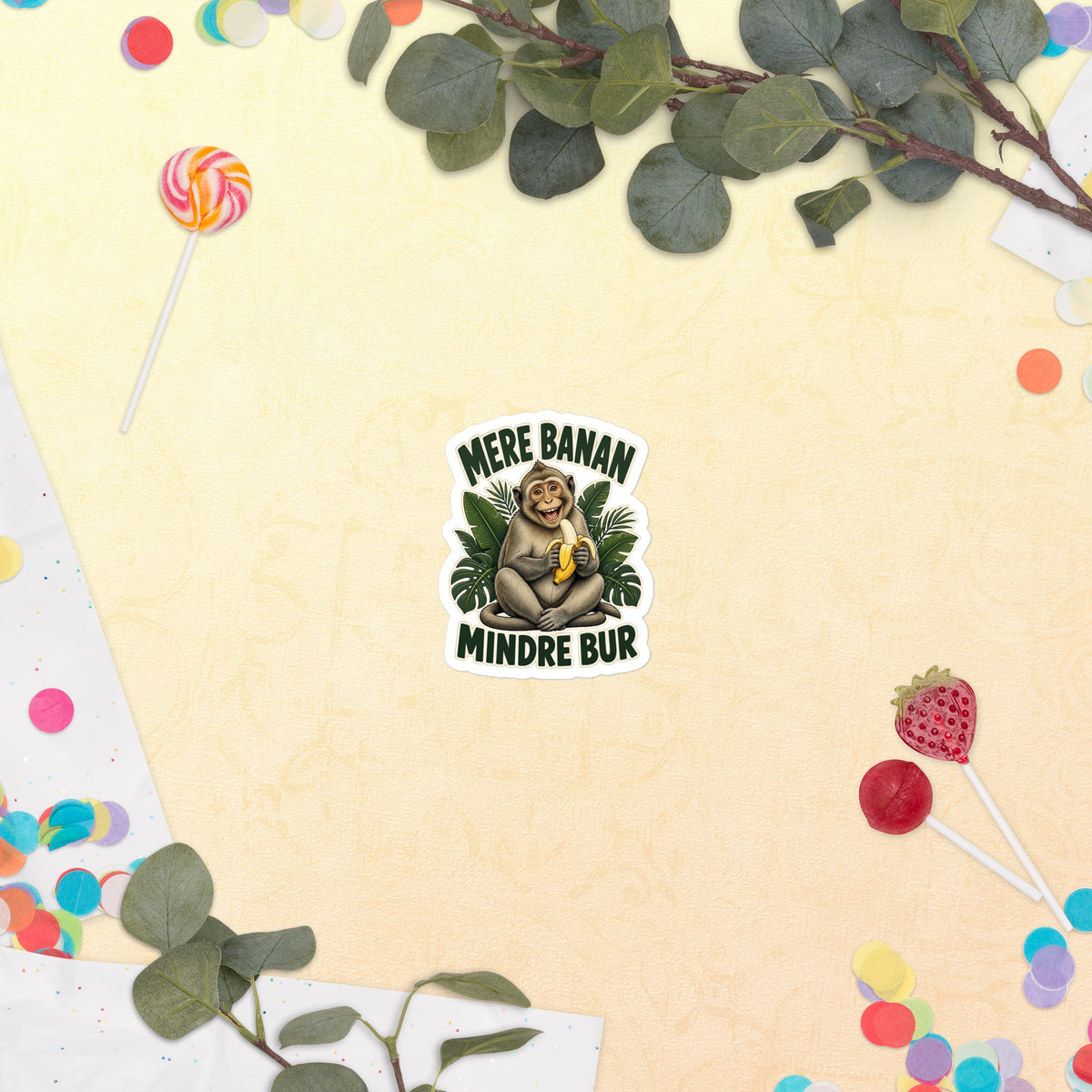 Klistermærke med teksten Mere banan, mindre bur og en glad abe med en banan, 7,5 x 7,5 cm, på en lys baggrund med blomster