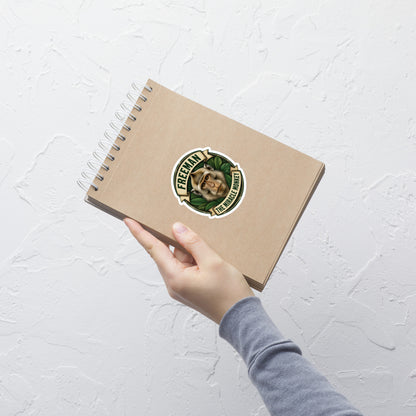 Klistermærke med Freeman The Miracle Monkey badge med en abe i grønt, 10 x 10 cm, på en notesbog