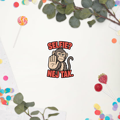 Klistermærke med teksten Selfie? Nej tak og en abe der holder hånden op, 10 x 10 cm, på en hvid baggrund med blomster