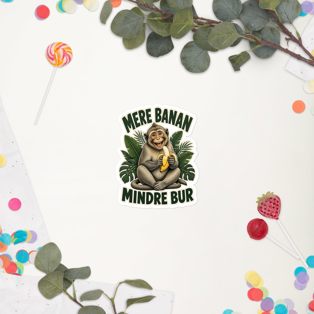 Klistermærke med teksten Mere banan, mindre bur og en glad abe med en banan, 10 x 10 cm, på en hvid baggrund med blomster