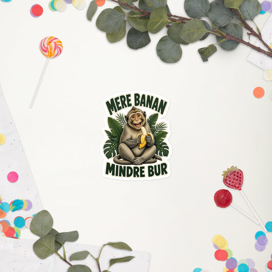 Klistermærke med teksten Mere banan, mindre bur og en glad abe med en banan, 10 x 10 cm, på en hvid baggrund med blomster