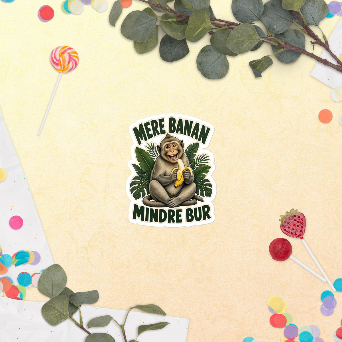Klistermærke med teksten Mere banan, mindre bur og en glad abe med en banan, 10 x 10 cm, på en lys baggrund med blomster