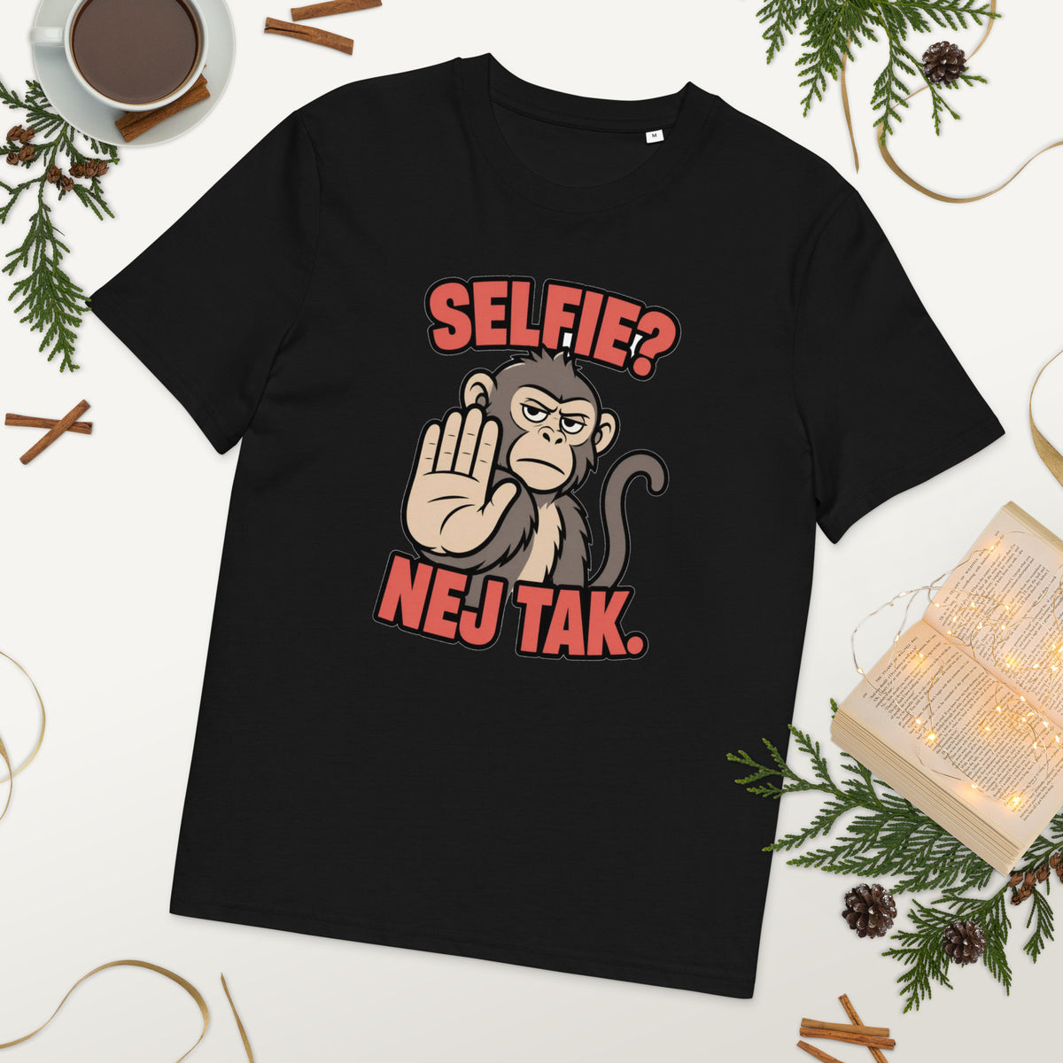 Sjov abe t-shirt med teksten Selfie? Nej tak. i farven sort, lagt på et bord med kaffe og grønt