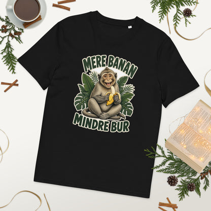 Abe t-shirt med teksten Mere banan, mindre bur i farven sort, lagt på et bord med kaffe og grønt