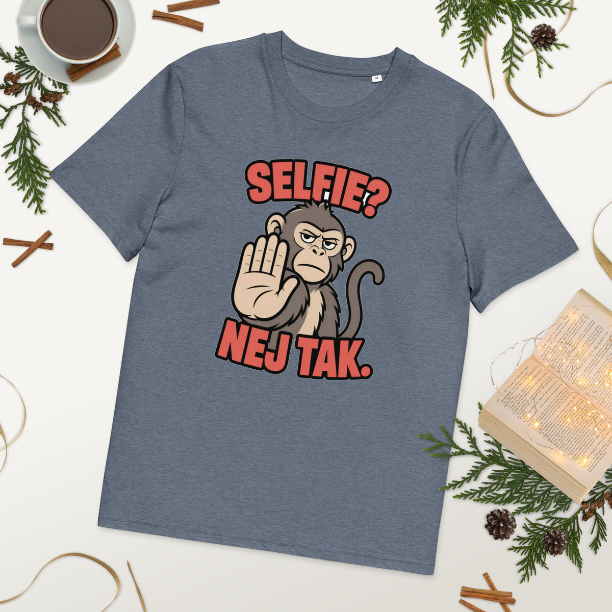 Sjov abe t-shirt med teksten Selfie? Nej tak. i farven blågrå meleret, lagt på et bord med kaffe og grønt