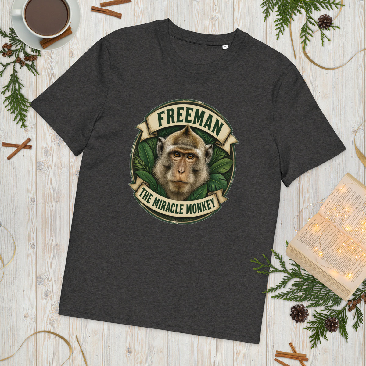Freeman The Miracle Monkey t-shirt med abe i grønt badge i farven mørkegrå meleret, lagt på et lyst træbord
