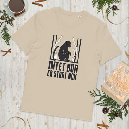 T-shirt med teksten Intet bur er stort nok i farven sand, lagt på et lyst træbord