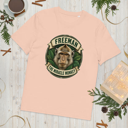 Freeman The Miracle Monkey t-shirt med abe i grønt badge i farven fersken, lagt på et lyst træbord