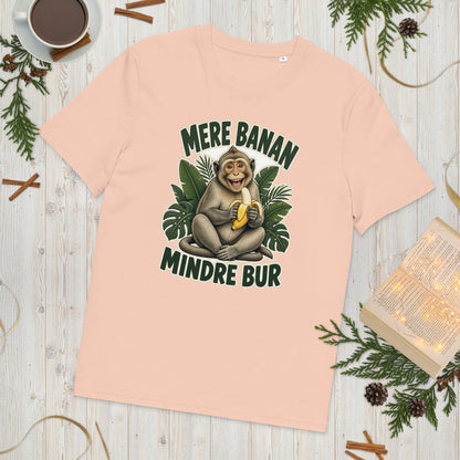 Abe t-shirt med teksten Mere banan, mindre bur i farven fersken, lagt på et lyst træbord