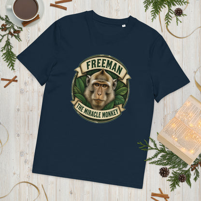 Freeman The Miracle Monkey t-shirt med abe i grønt badge i farven marineblå, lagt på et lyst træbord