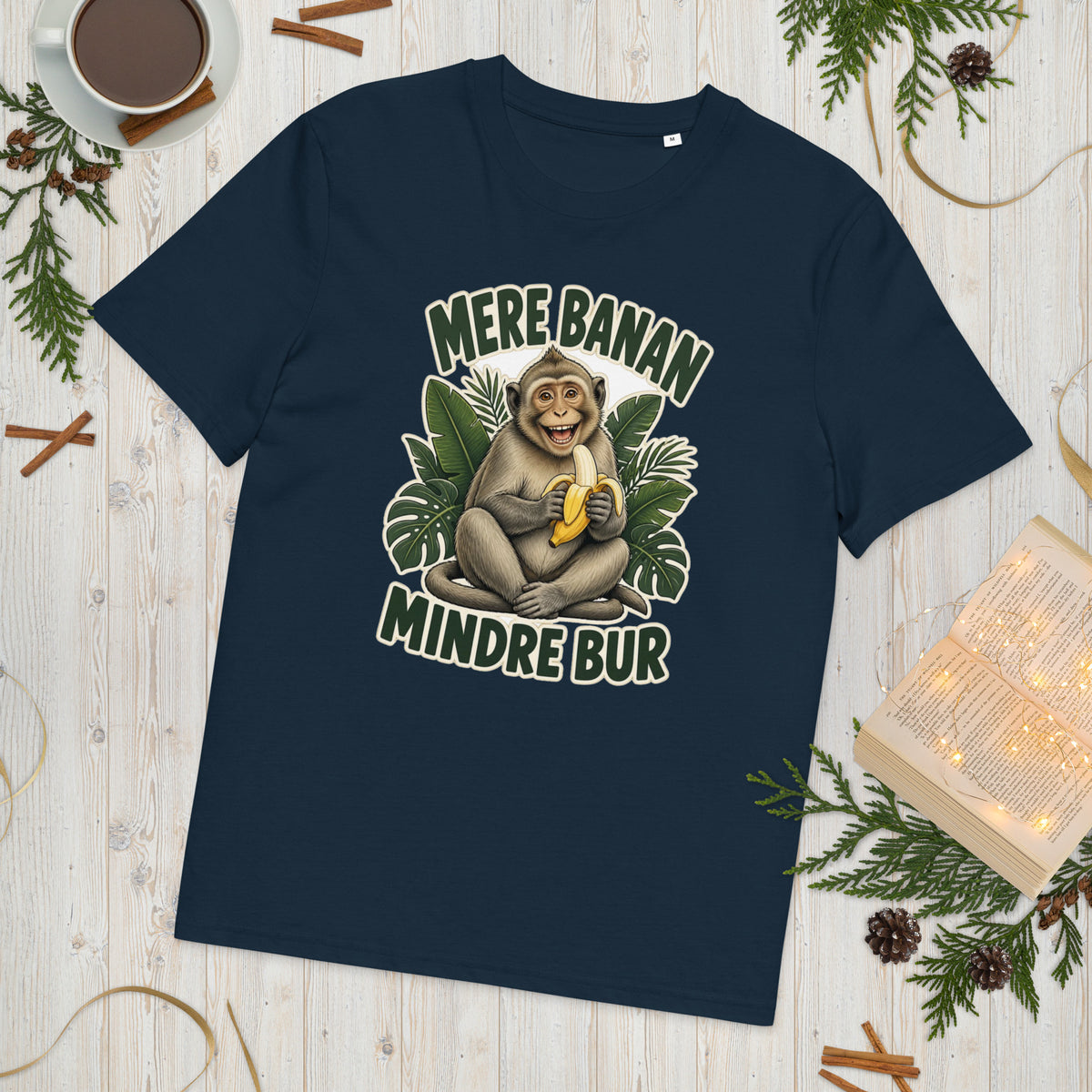 Abe t-shirt med teksten Mere banan, mindre bur i farven marineblå, lagt på et lyst træbord