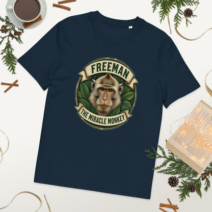 Freeman The Miracle Monkey t-shirt med abe i grønt badge i farven marineblå, lagt på et bord med kaffe og grønt