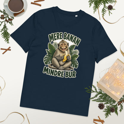 Abe t-shirt med teksten Mere banan, mindre bur i farven marineblå, lagt på et bord med kaffe og grønt