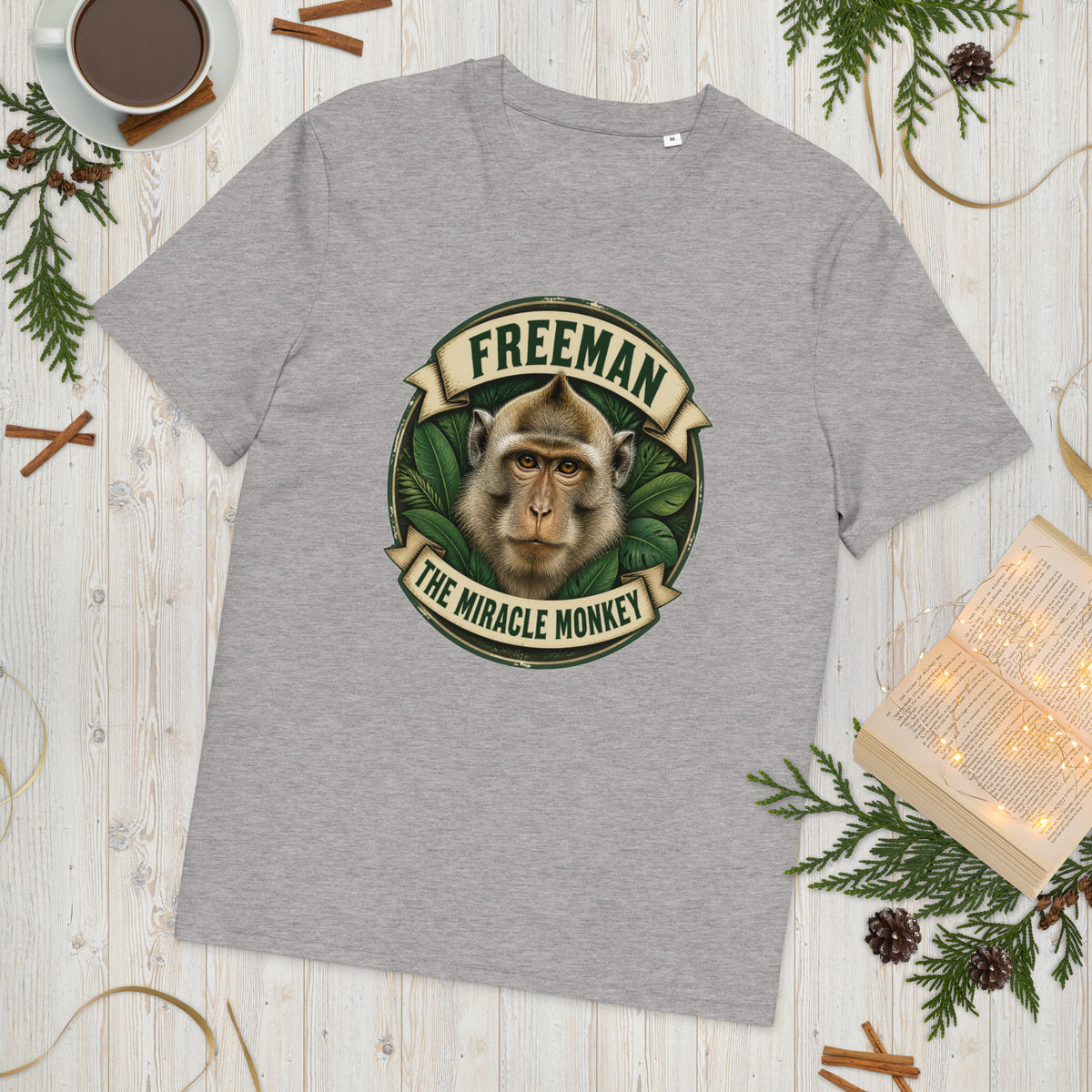 Freeman The Miracle Monkey t-shirt med abe i grønt badge i farven lysegrå meleret, lagt på et lyst træbord