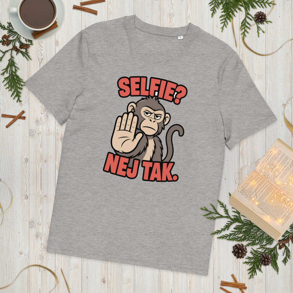 Sjov abe t-shirt med teksten Selfie? Nej tak. i farven lysegrå meleret, lagt på et lyst træbord