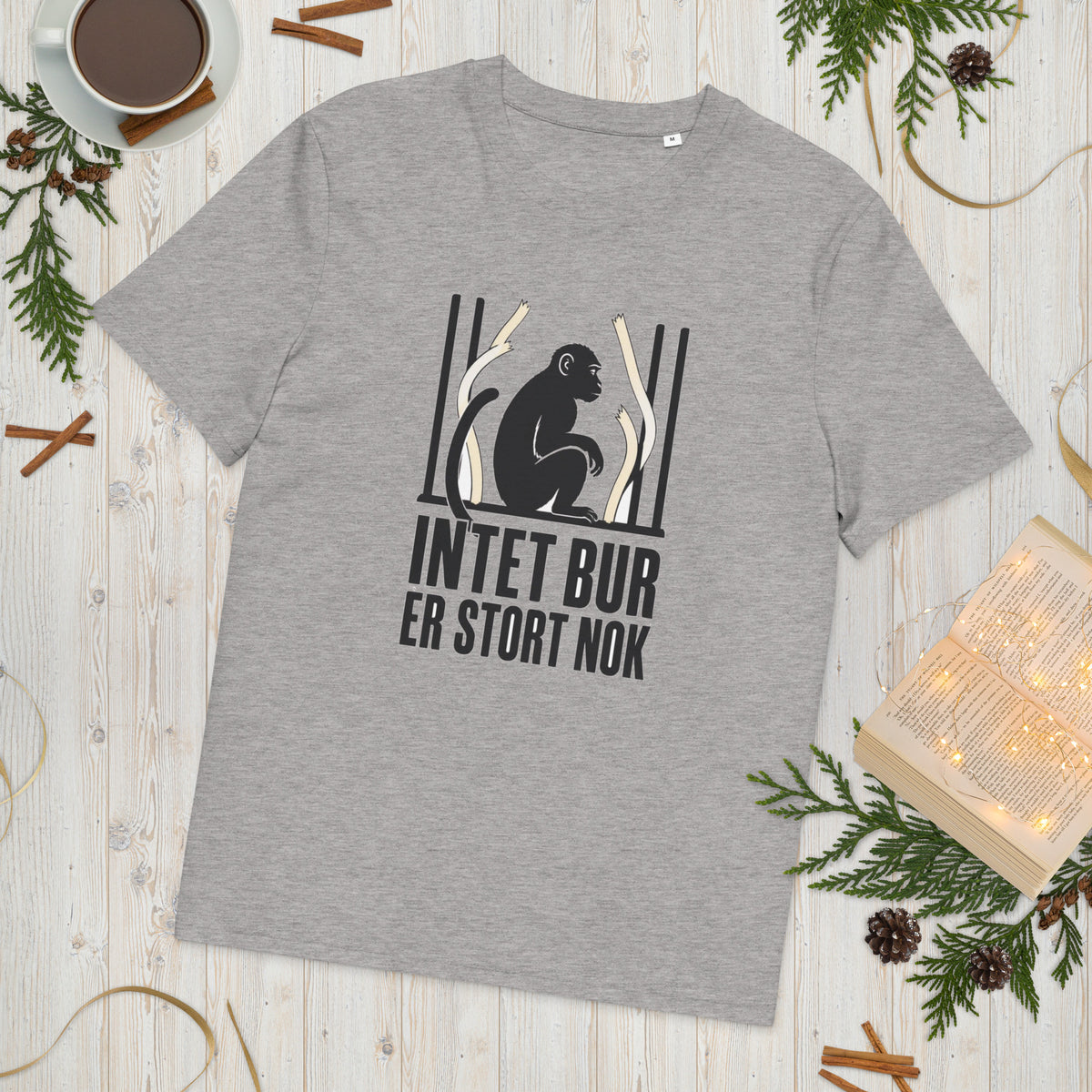T-shirt med teksten Intet bur er stort nok i farven lysegrå meleret, lagt på et lyst træbord