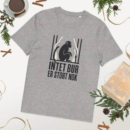 T-shirt med teksten Intet bur er stort nok i farven lysegrå meleret, lagt på et bord med kaffe og grønt