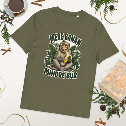 Abe t-shirt med teksten Mere banan, mindre bur i farven khaki, lagt på et bord med kaffe og grønt
