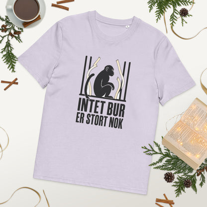 T-shirt med teksten Intet bur er stort nok i farven lavendel, lagt på et bord med kaffe og grønt