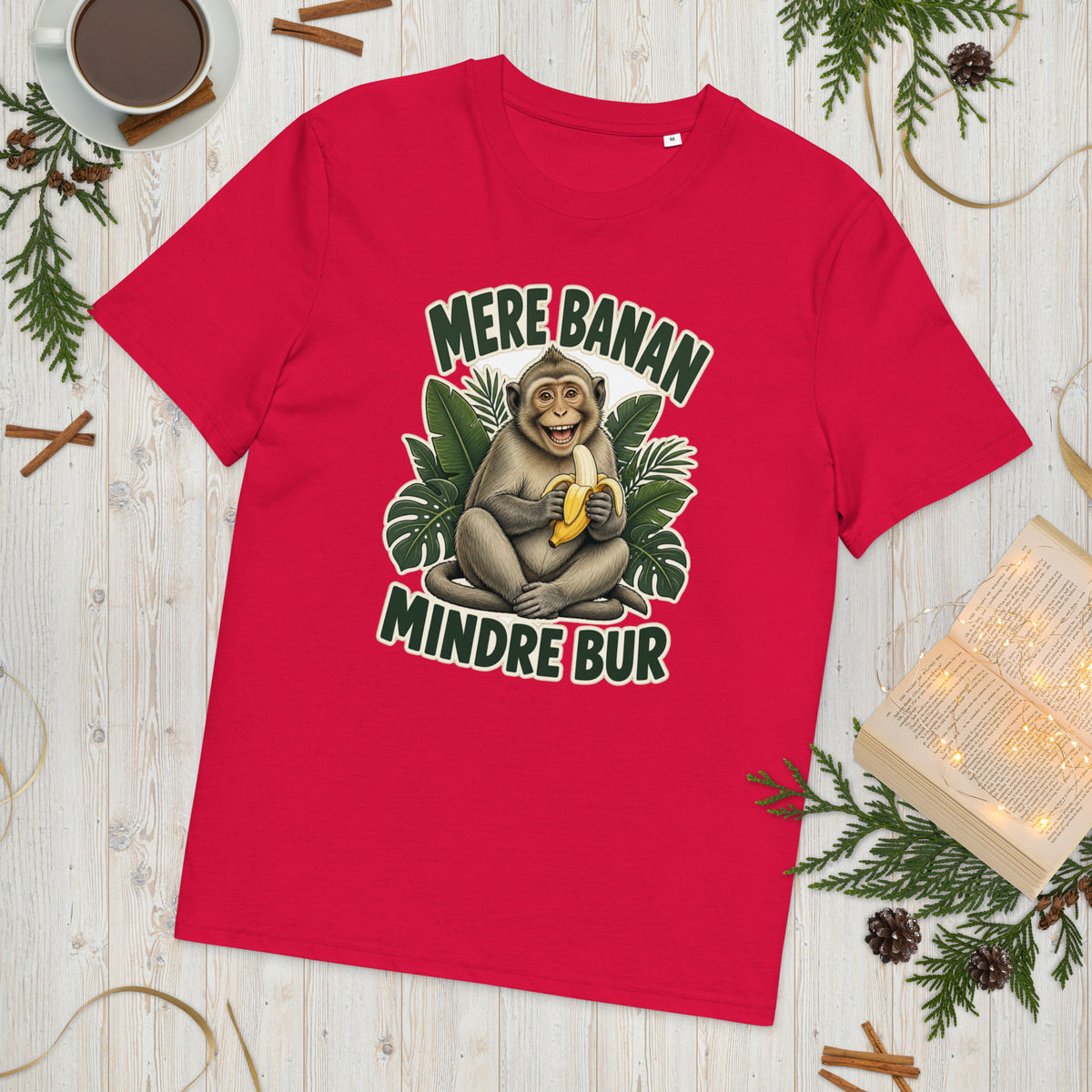 Abe t-shirt med teksten Mere banan, mindre bur i farven rød, lagt på et lyst træbord