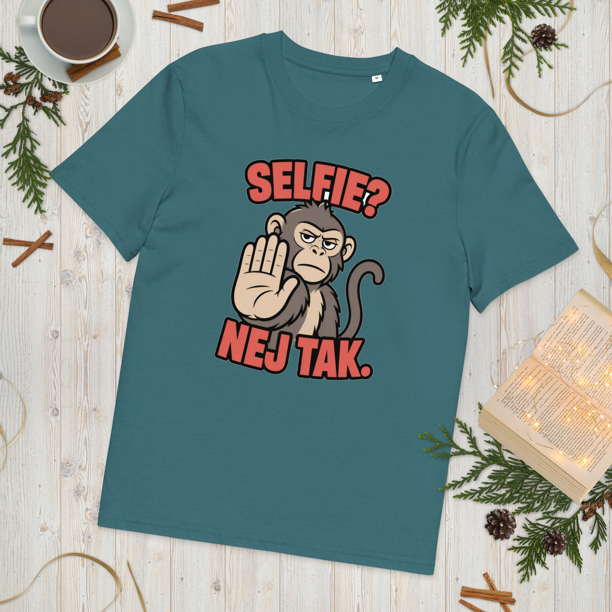 Sjov abe t-shirt med teksten Selfie? Nej tak. i farven petroleumsblå, lagt på et lyst træbord