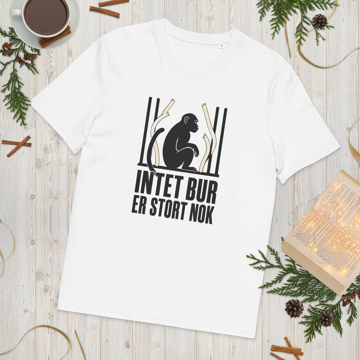 T-shirt med teksten Intet bur er stort nok i farven hvid, lagt på et lyst træbord