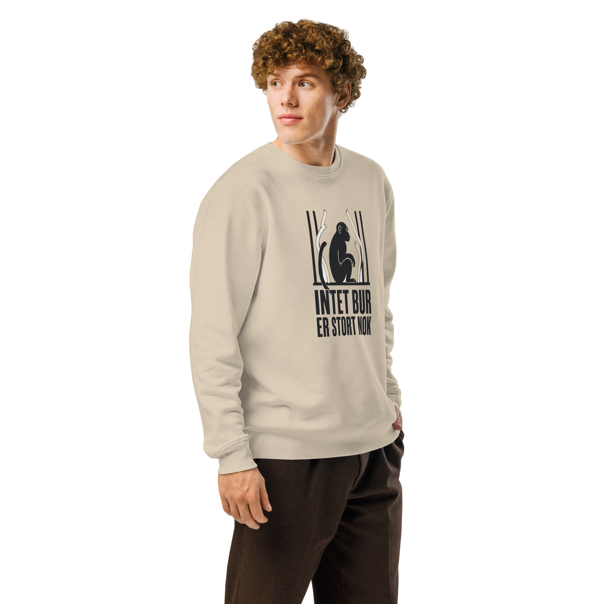 Sweatshirt med teksten Intet bur er stort nok og en abe bag tremmer i farven sand, båret af en ung mand, set skråt