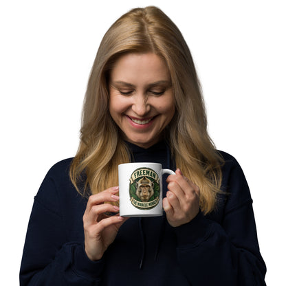 Hvidt keramikkrus med Freeman The Miracle Monkey badge med en abe i grønt, holdt af en kvinde, set fra den anden side