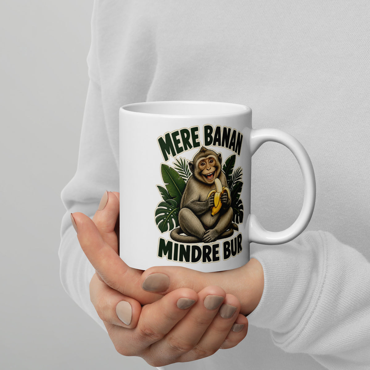 Hvidt keramikkrus med teksten Mere banan, mindre bur og en glad abe med en banan, holdt i hænderne, hank til højre